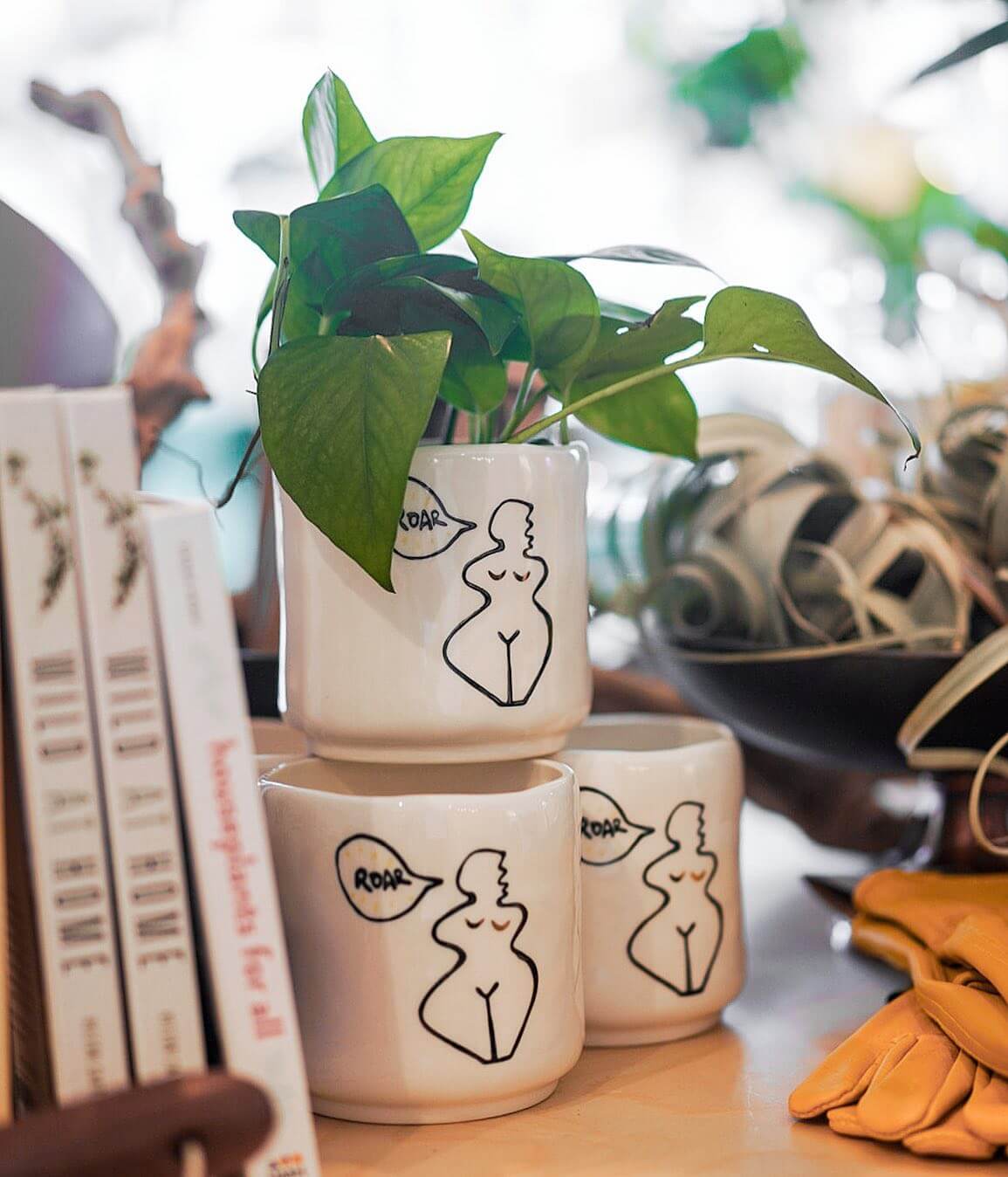 Three white ceramic planters featuring minimalist line art of a curvy figure and the word 