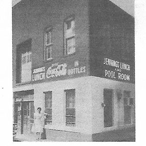 Black and white photograph of a two-story brick building with signs reading 