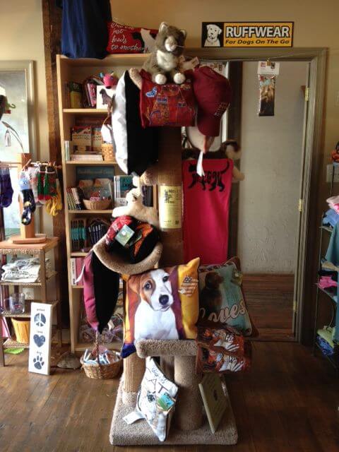 A pet supply store display featuring various dog-themed items such as pillows, toys, and clothing. A sign above reads