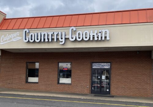 A brick-front restaurant with a red roof and a white sign that reads 