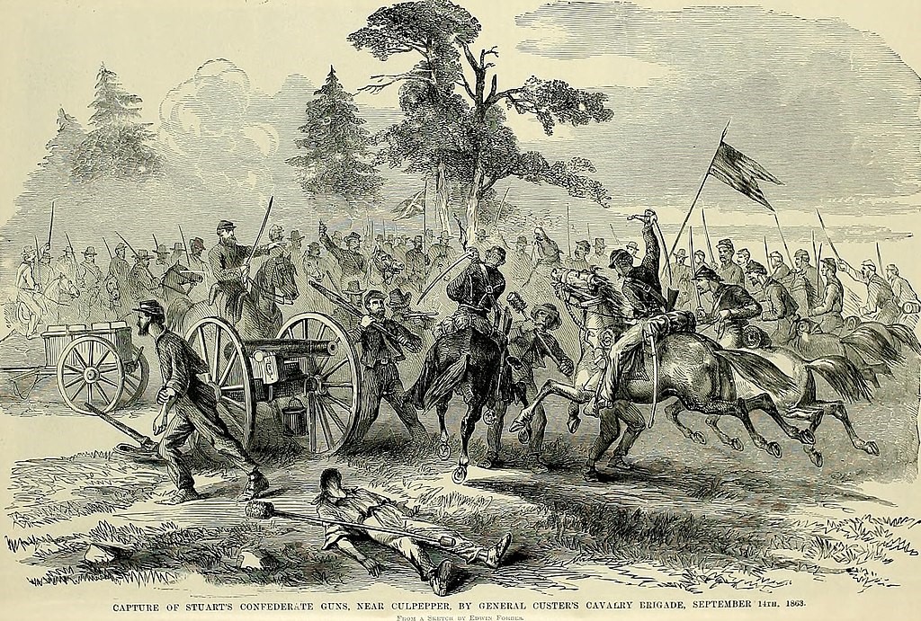 Illustration of a historical battle scene with mounted soldiers and infantry engaging in combat. A fallen soldier lies on the ground, while others advance amidst gunfire and smoke. The scene is titled “Capture of Stuart’s Confederate Guns Near Culpeper by General Custer’s Cavalry, September 14th, 1863.