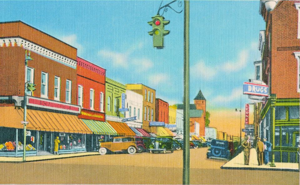 A vintage illustration of a busy downtown street, reminiscent of Culpeper Walk, with colorful two-story buildings housing various storefronts, including a charming drugstore. Classic cars are parked along the street as a green traffic light hangs overhead. People are gathered on the bustling sidewalk.
