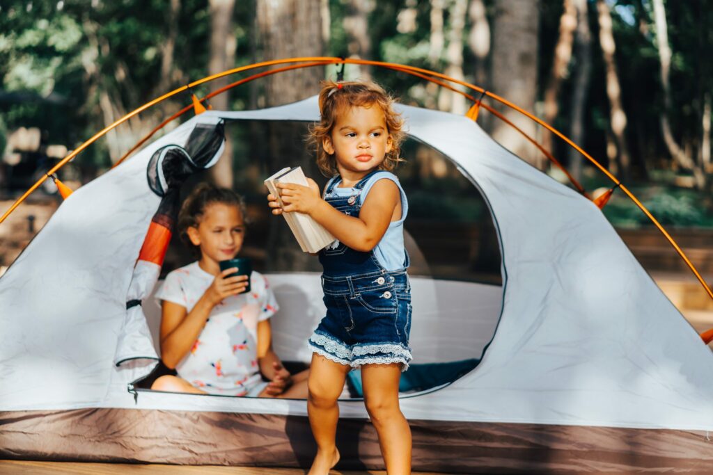 two children playing at a campsite in front of a tent