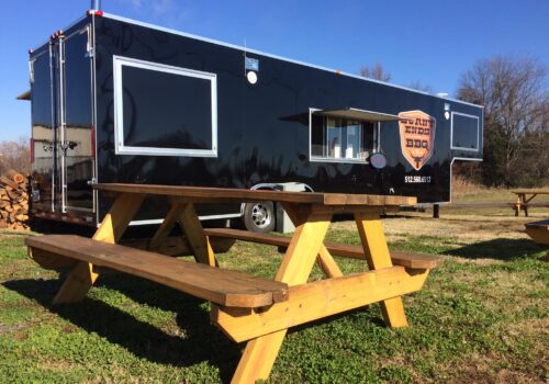 food truck with a sign reading Burnt Ends and a picnic table in front Image