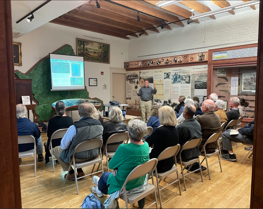 group of people sitting in a museum listening to a lecture