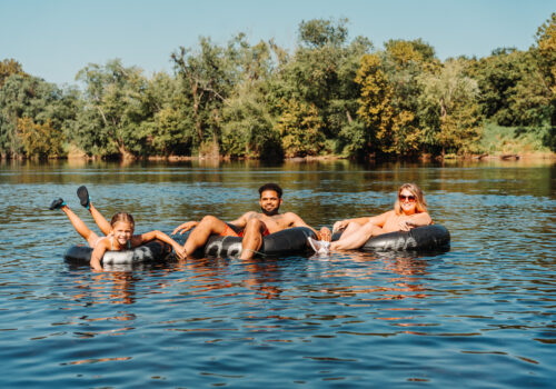 three people in a tube floating on a river Image