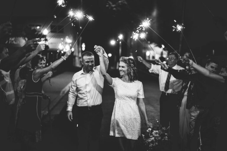 couple holding hands and standing under guests holding sparklers