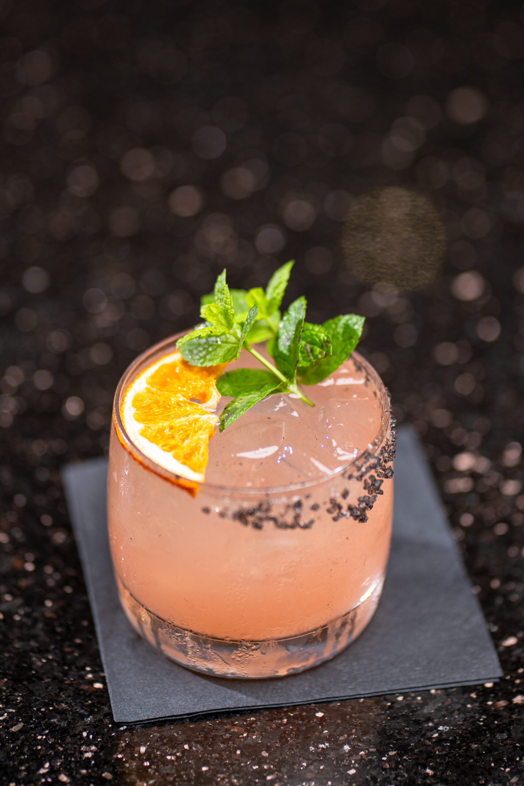 a pink cocktail decorated with a green herb