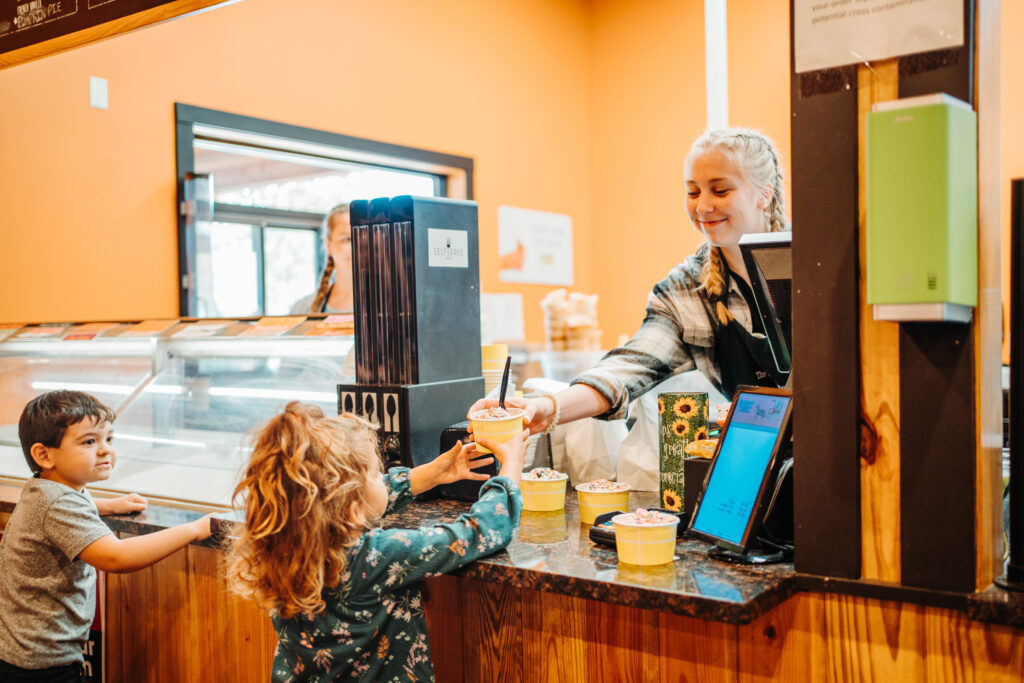 two kids receiving ice cream over a counter
