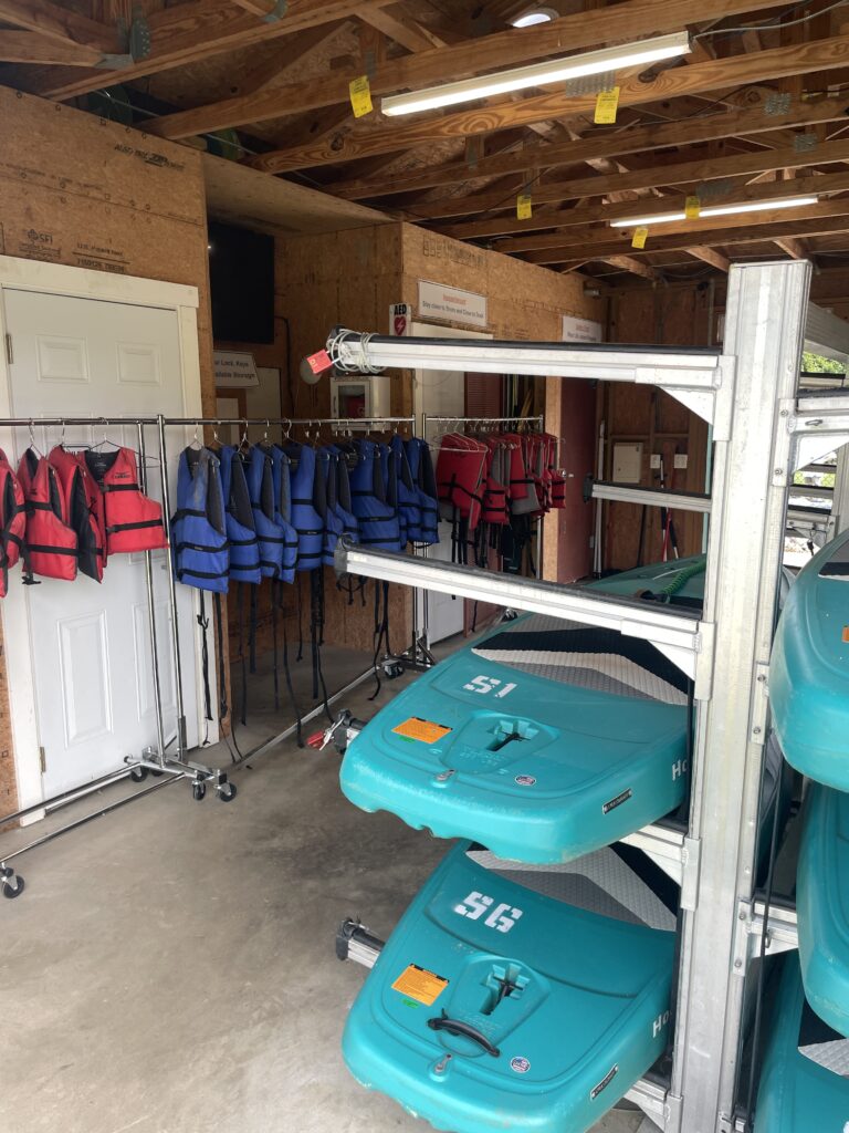 life vest lined up on a rack and boats in a storage shed