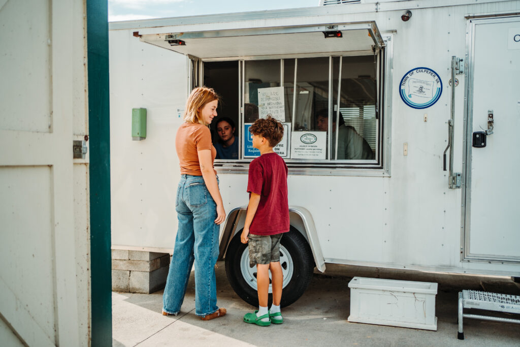 two people in front of a check in trailer